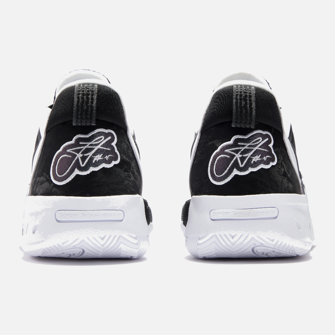 Black and white sneakers with brand logo on a light gray background